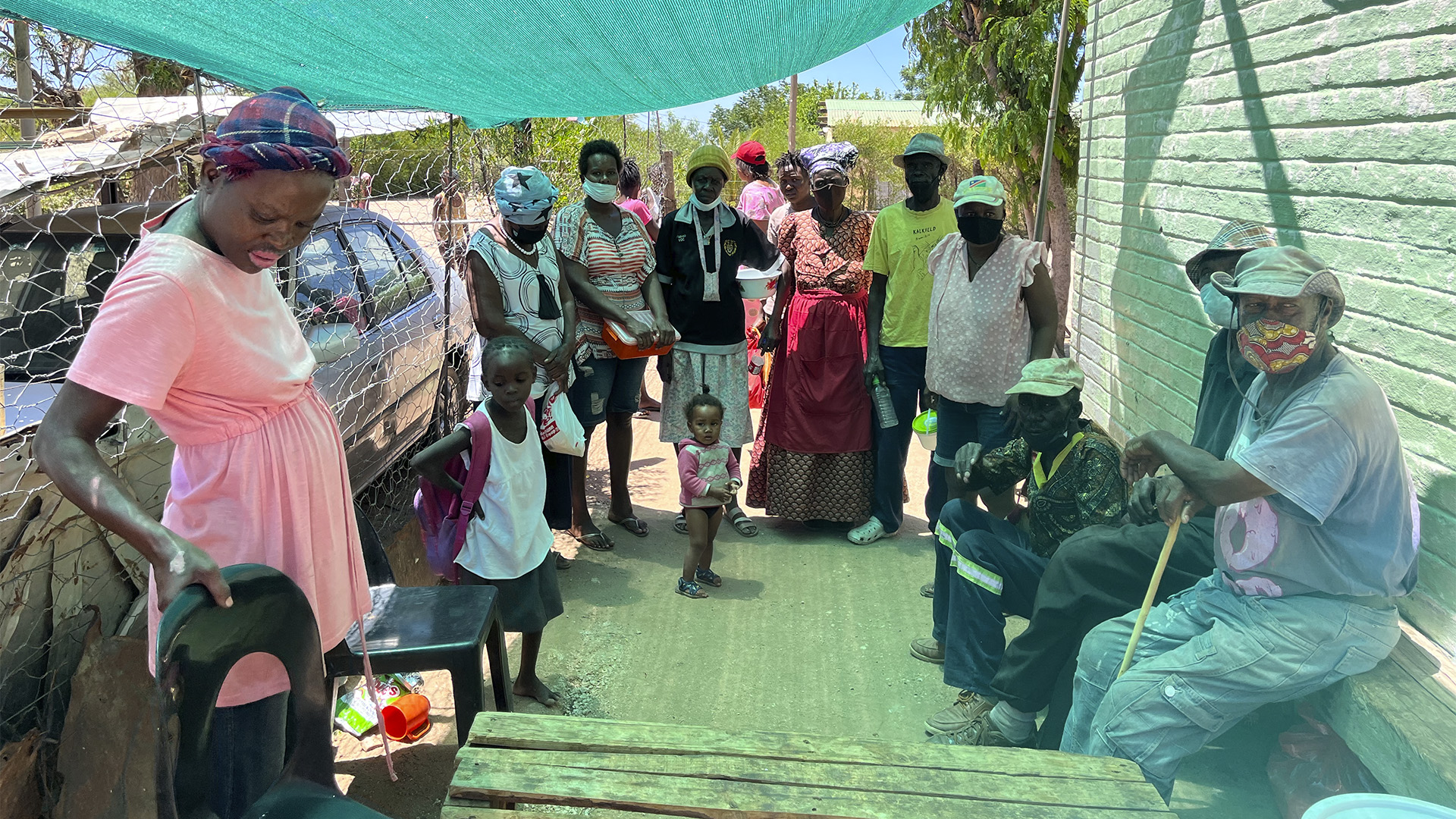 Besonders hilfsbedürftige Dorfbewohner:innen warten auf das Essen in der Suppenküche, die von engagierten Frauen betrieben wird